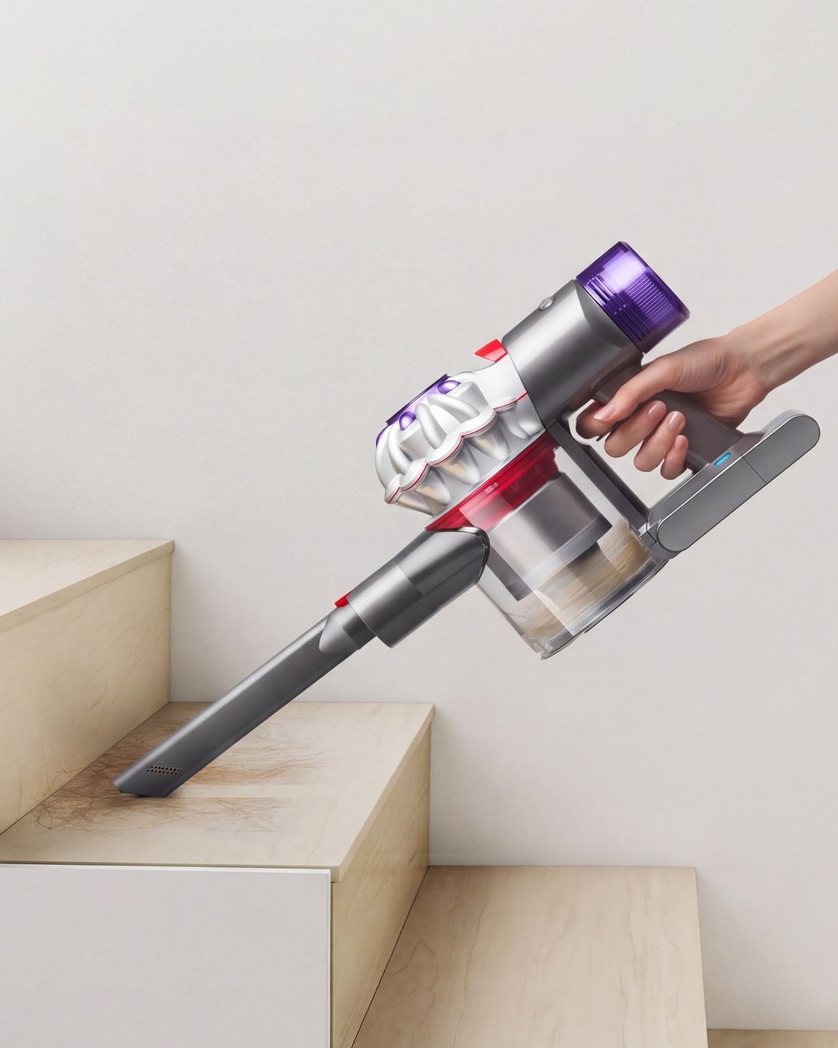 The Dyson Car+Boat handheld vacuum with the crevice tool cleaning a stair case.